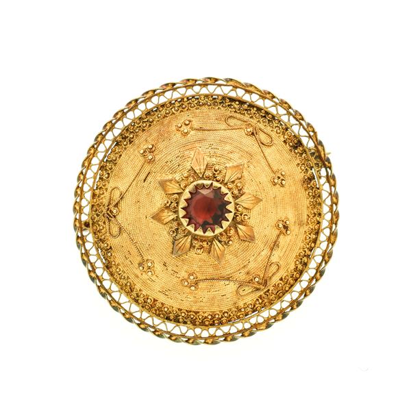 Brooch in yellow gold and red stone