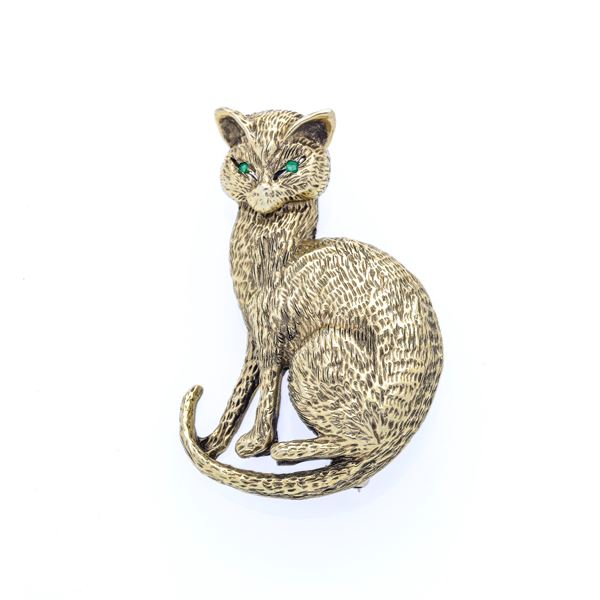 Cat brooch in gold with a low title and emeralds