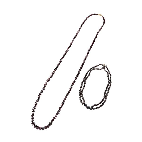 A long necklace in garnet and low gold and another, two strands, in garnet and yellow gold