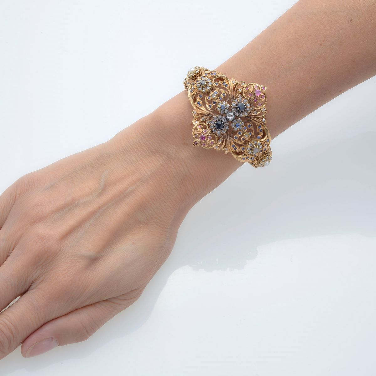 Bracciale rigido a volute floreali in oro 18 kt, rose di diamante, zaffiri, rubini e perle