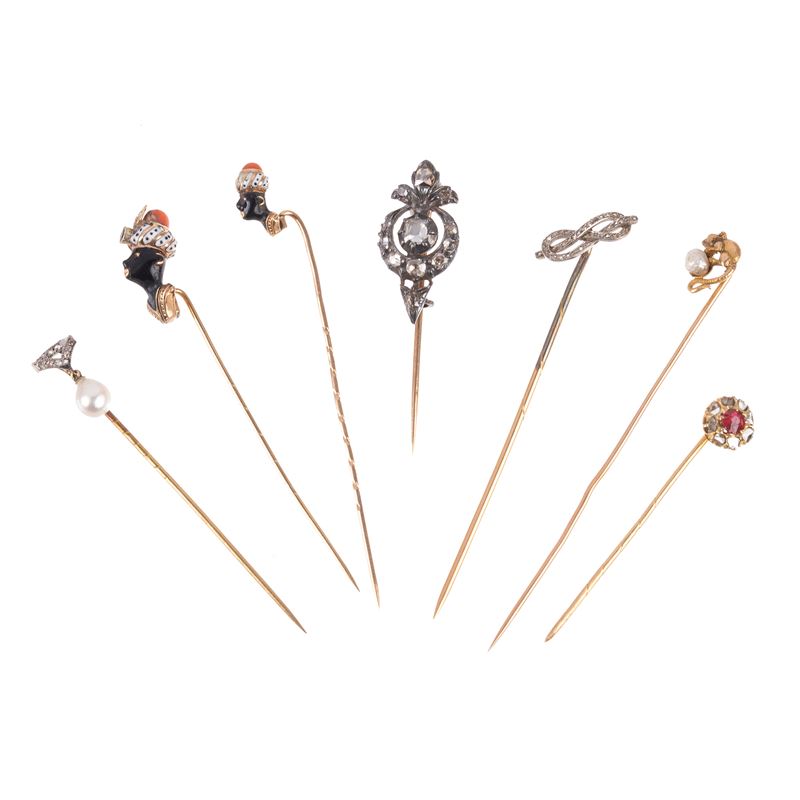 Sette splle da cappello e cravatta in oro 18 kt, oro basso, argento, diamanti, smalti, corallo