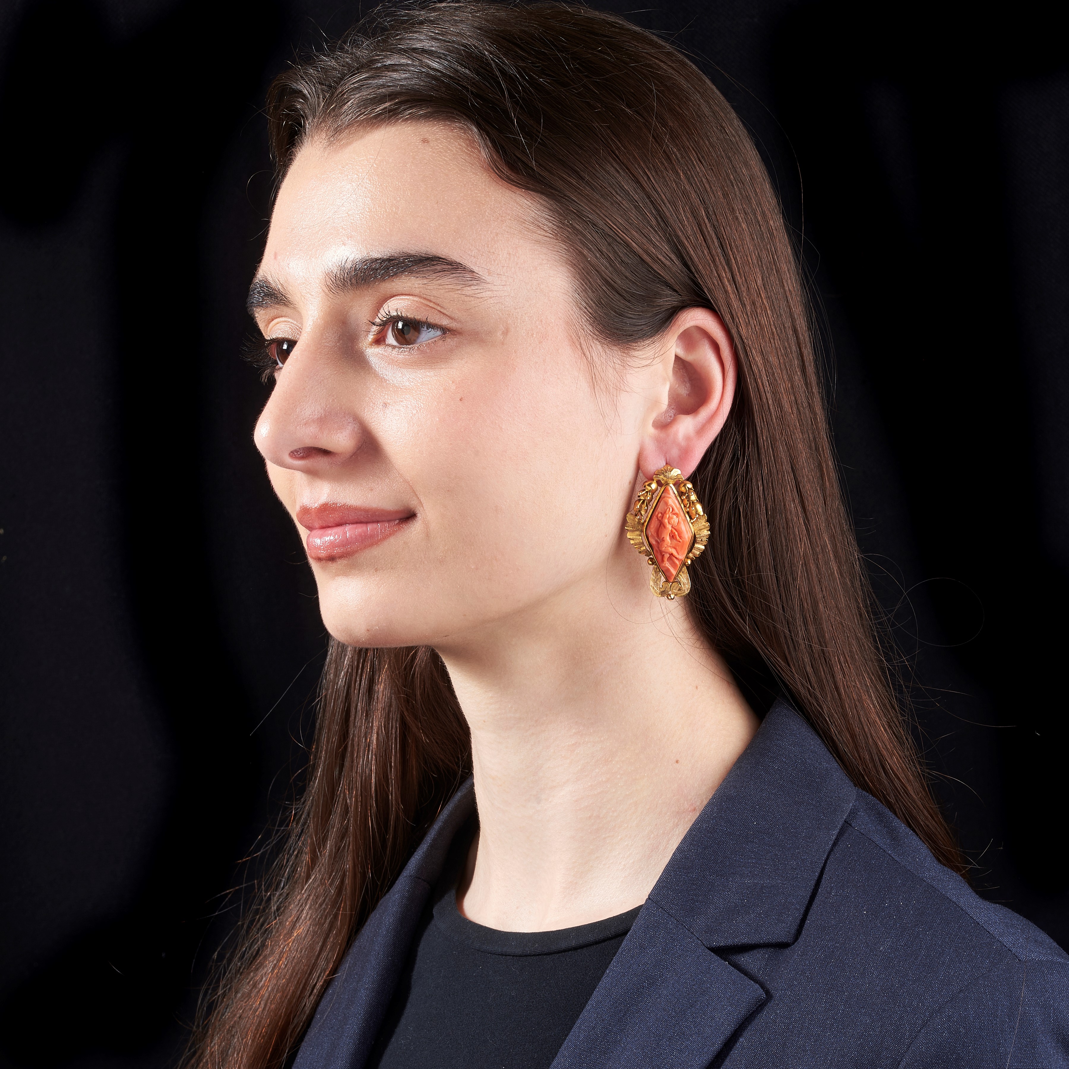 Paio di orecchini pendenti in oro giallo 12 kt e corallo inciso con putti